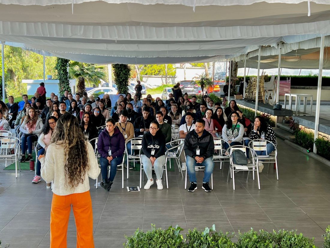 Paulina, de espaldas, frente a un auditorio en un evento corporativo al aire libre